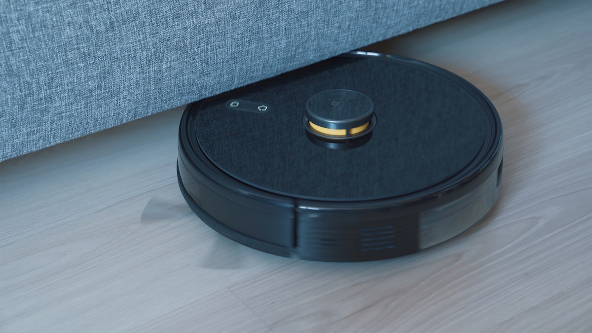 Robô aspirador preto limpando piso de madeira